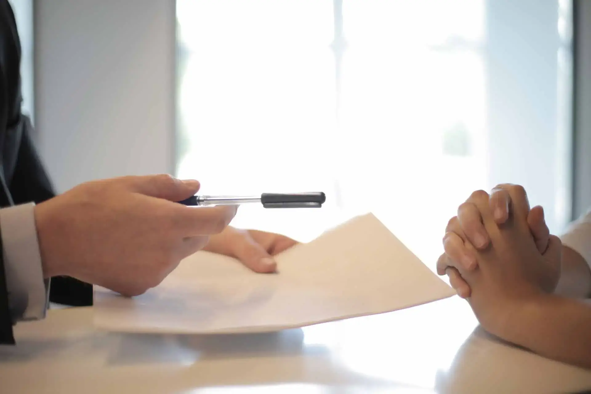 Close-up van een hand met een pen die een contract ondertekent, symbolisch voor het aangaan van een uitzendovereenkomst.