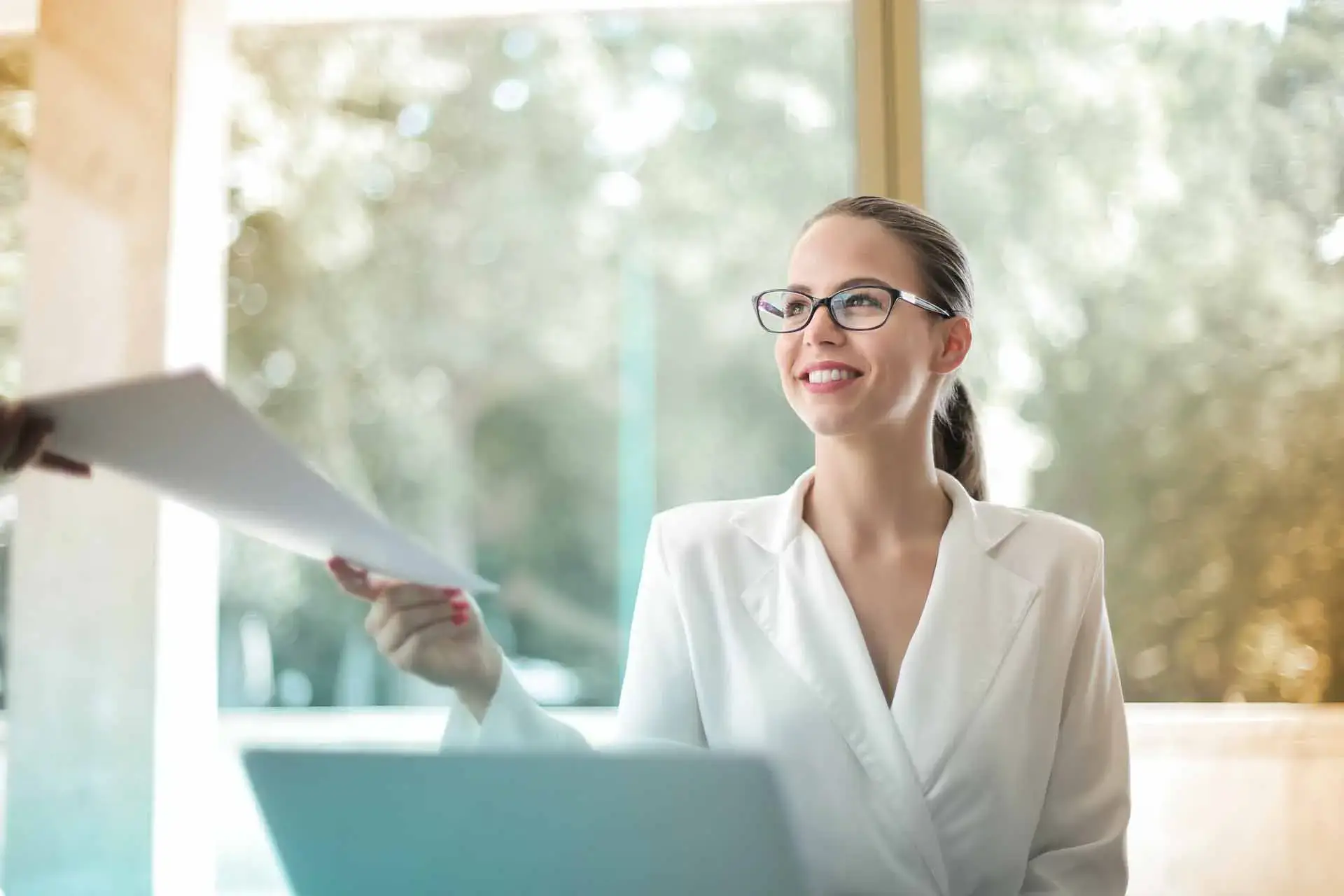 akelijke vrouw achter een bureau, representatief voor de verantwoordelijkheden bij uitzenden voor zowel werkgevers als uitzendorganisaties.