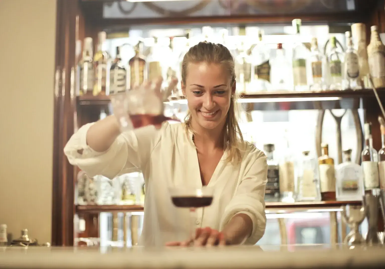 Vrouw die werkt achter een bar, representatief voor de doelgroep van uitzenden en de flexibiliteit die het biedt.