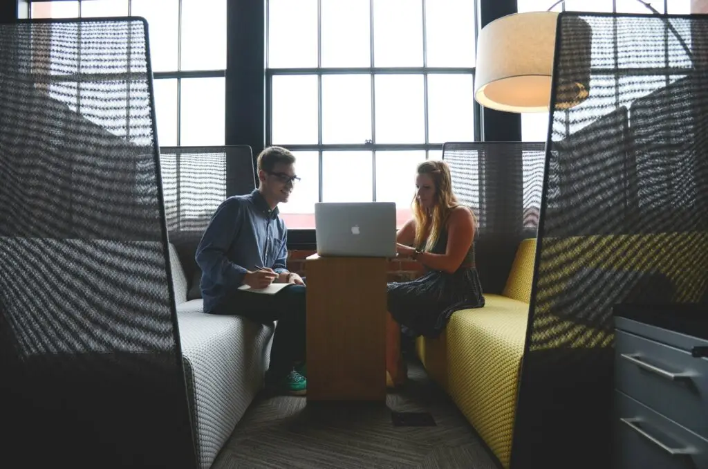 Twee collega's in gesprek in een moderne kantooromgeving, symbolisch voor payroll en werkgeverschap.