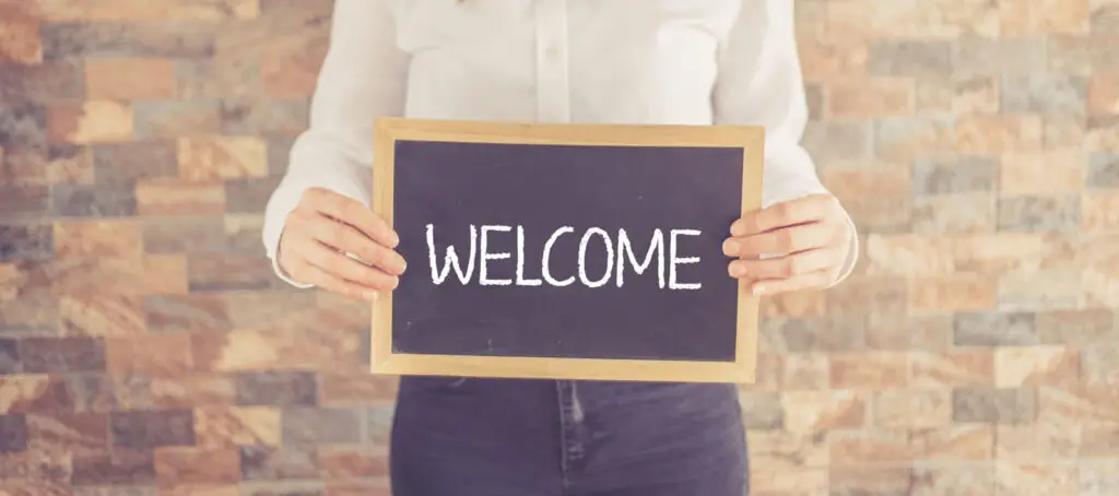 Afbeelding van een persoon die een bord met het woord 'Welcome' vasthoudt, passend bij een artikel over de regels rond de proeftijd, inclusief de duur en wanneer er geen proeftijd van toepassing is.