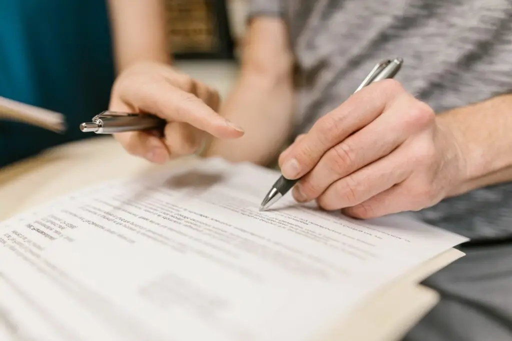 Afbeelding van een hand die een pen vasthoudt terwijl een document wordt ondertekend, passend bij een artikel dat uitleg geeft over het opstellen van een arbeidsovereenkomst. Het artikel bevat tips zoals het vastleggen van belangrijke afspraken en het controleren van vertegenwoordigingsbevoegdheid.