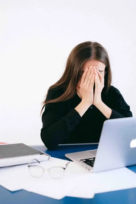 Afbeelding van een persoon die haar gezicht bedekt met haar handen, passend bij een artikel dat uitlegt wat de regels zijn rond ontslag tijdens de proeftijd en welke rechten de werknemer en werkgever hebben.