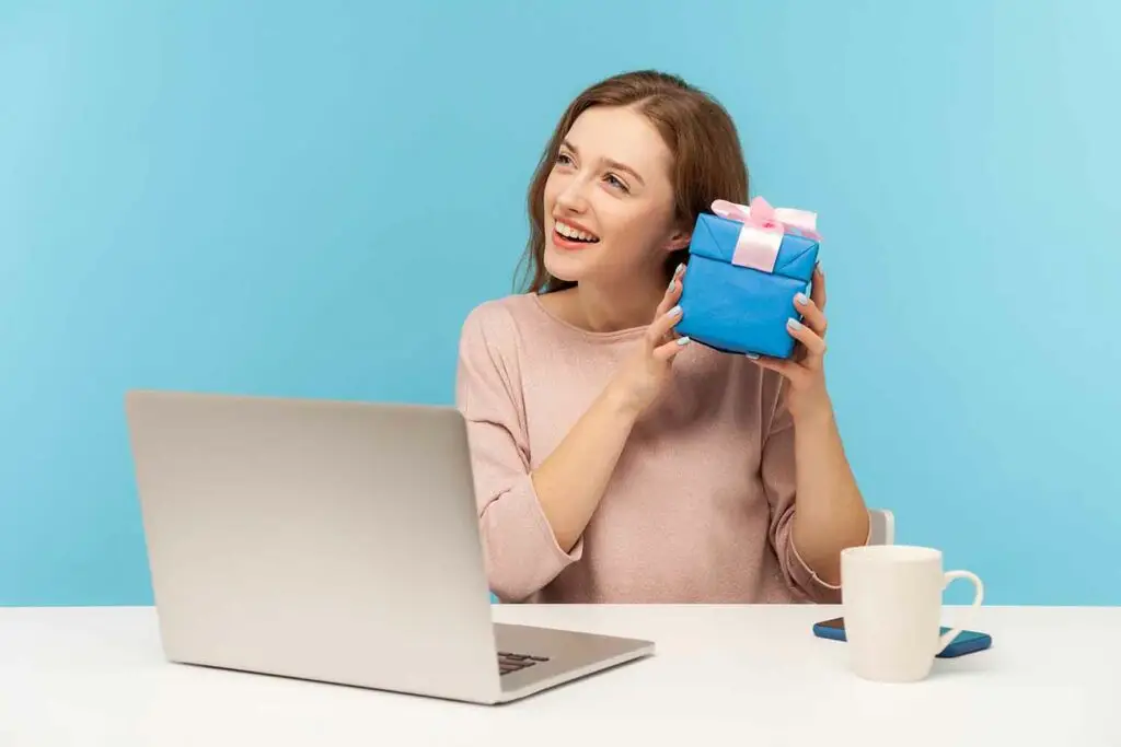 Afbeelding van een vrolijke vrouw met een cadeau, passend bij een artikel over de werkkostenregeling (WKR). Het stuk legt uit hoe werkgevers belastingvrije vergoedingen en verstrekkingen aan werknemers kunnen geven onder deze regeling.