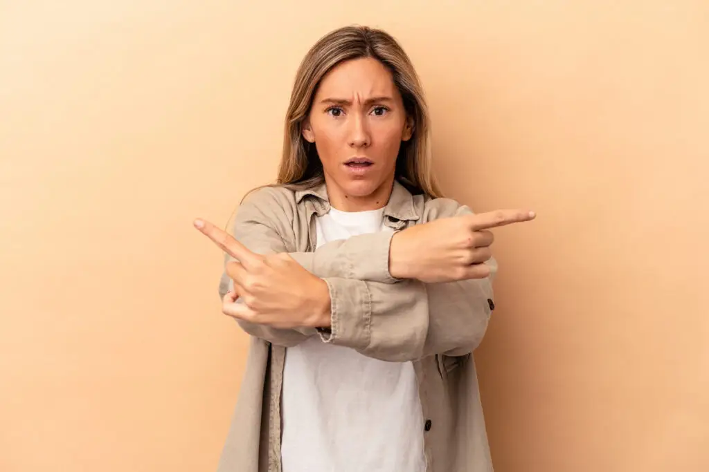 Vrouw die verbaasd naar de camera kijkt en wijst, symboliseert de verwarring en verschillen tussen payroll en salarisadministratie.