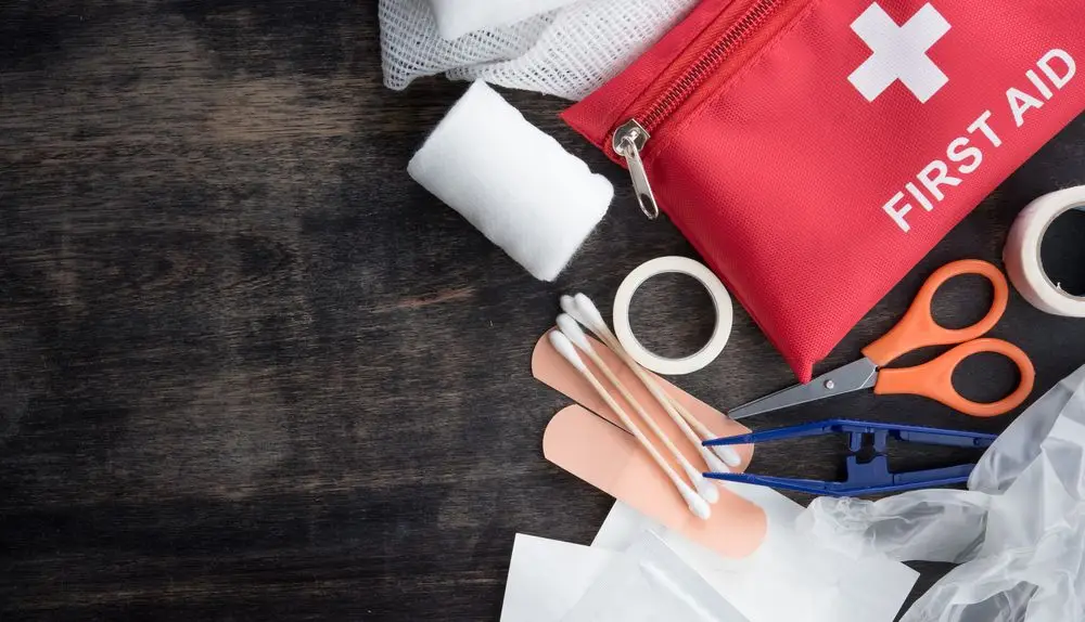 Afbeelding van EHBO-kit en veiligheidsmaterialen met informatie over de stappen die je moet nemen bij een bedrijfsongeval. Bevat instructies voor meldingsplicht en acties tijdens het ongeval.
