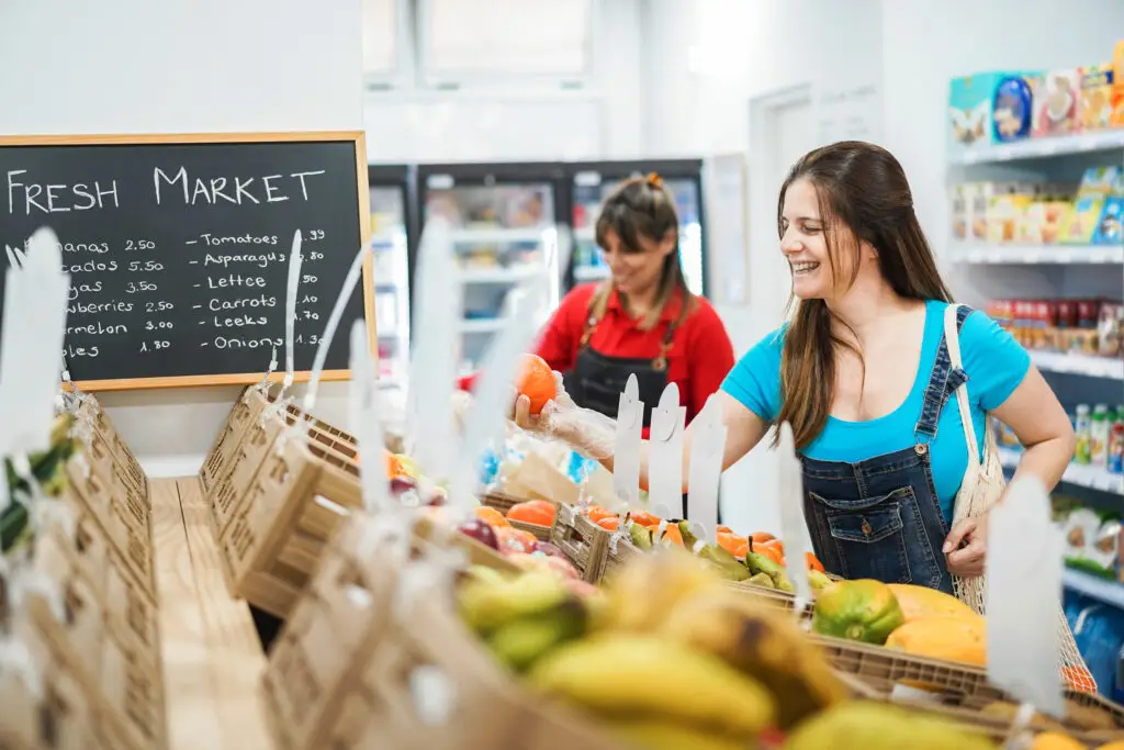 Afbeelding van twee vrouwelijke medewerkers in een winkelomgeving, bezig met het rangschikken van producten, illustratief voor twee payroll medewerkers die werkzaam zijn in de detailhandel.