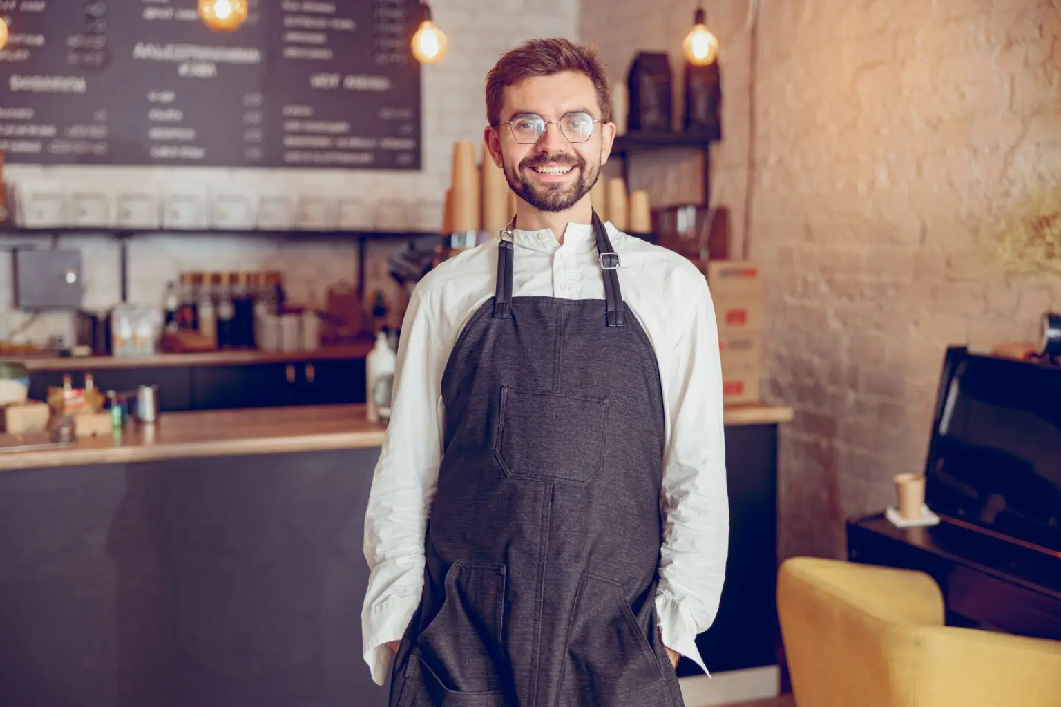 Afbeelding van een mannelijke horecamedewerker in een schort die glimlacht, met tekst over de voordelen van payroll voor horecabedrijven, inclusief kostenbesparing en flexibele contractopties.