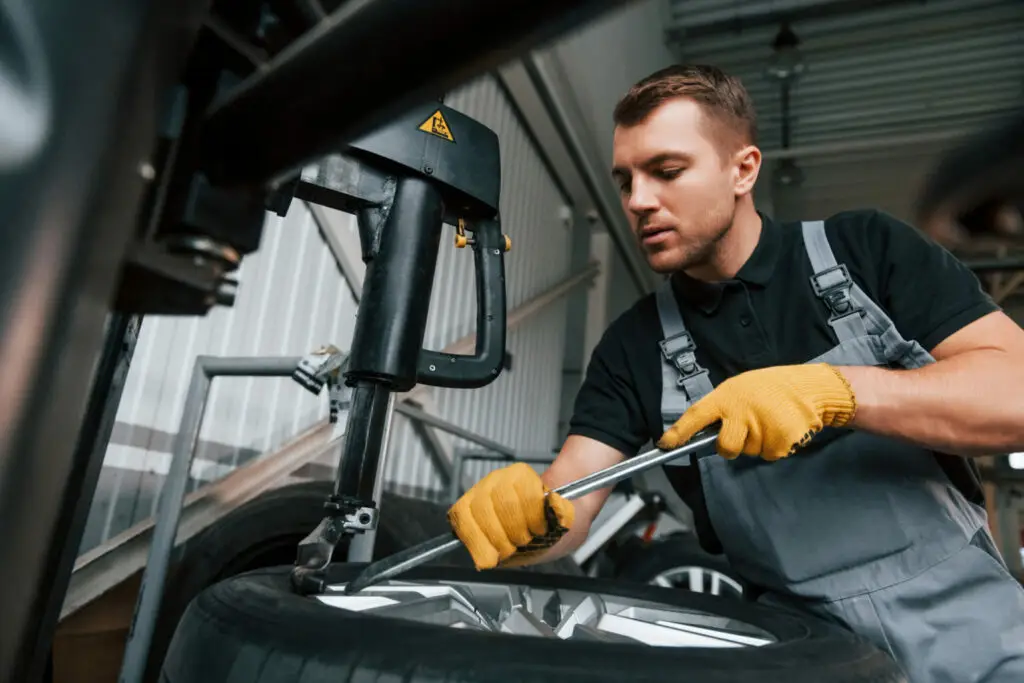 Een medewerker met veiligheidsuitrusting verricht onderhoudswerkzaamheden met focus, wat symbool staat voor de zorgvuldigheid en verantwoordelijkheid binnen payroll constructies en tegelijkertijd een representatie is van een payroll medewerker uit de maakindustrie.