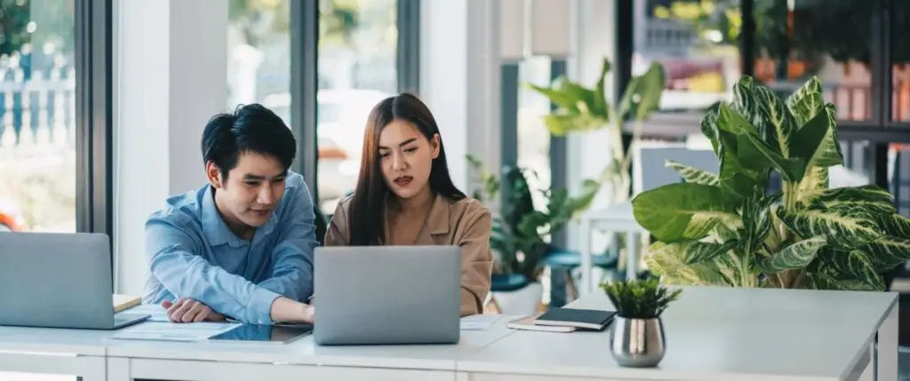 Een vrouwelijke manager leidt een nieuwe payroll-werknemer in tijdens een onboardinggesprek in een moderne kantooromgeving, met focus op begeleiding en integratie.